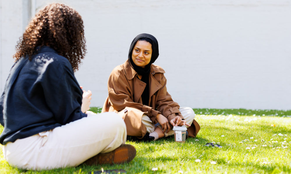 Two students sitting and talking on the grass