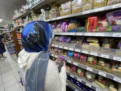 Woman standing in a supermarket aisle looking at goods. 