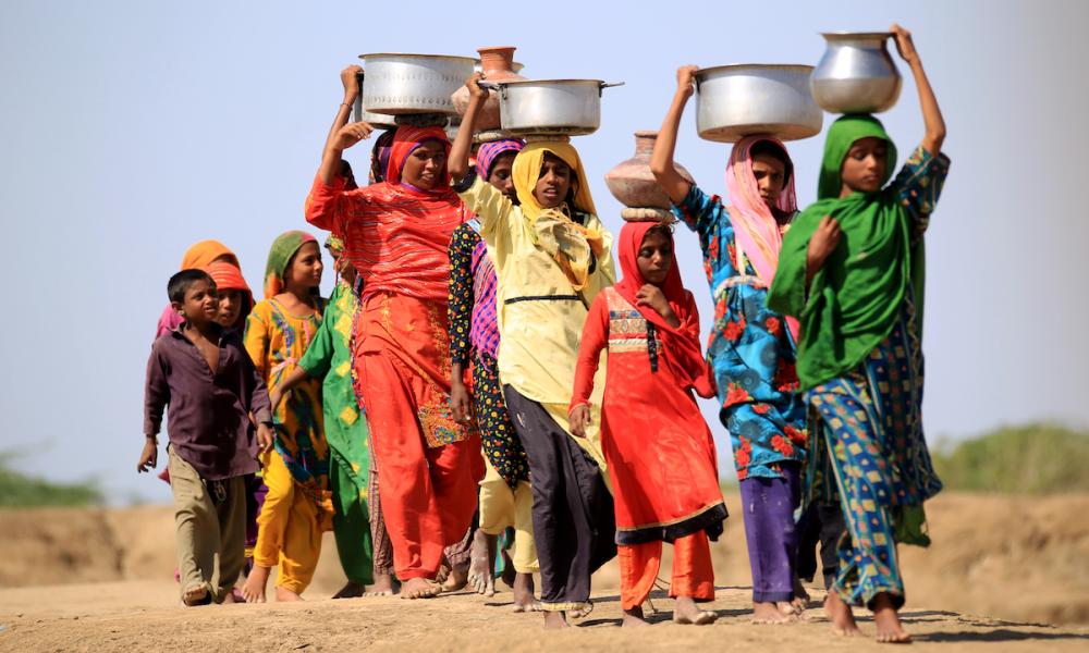 A line of women and children carrying pots in Pakistan