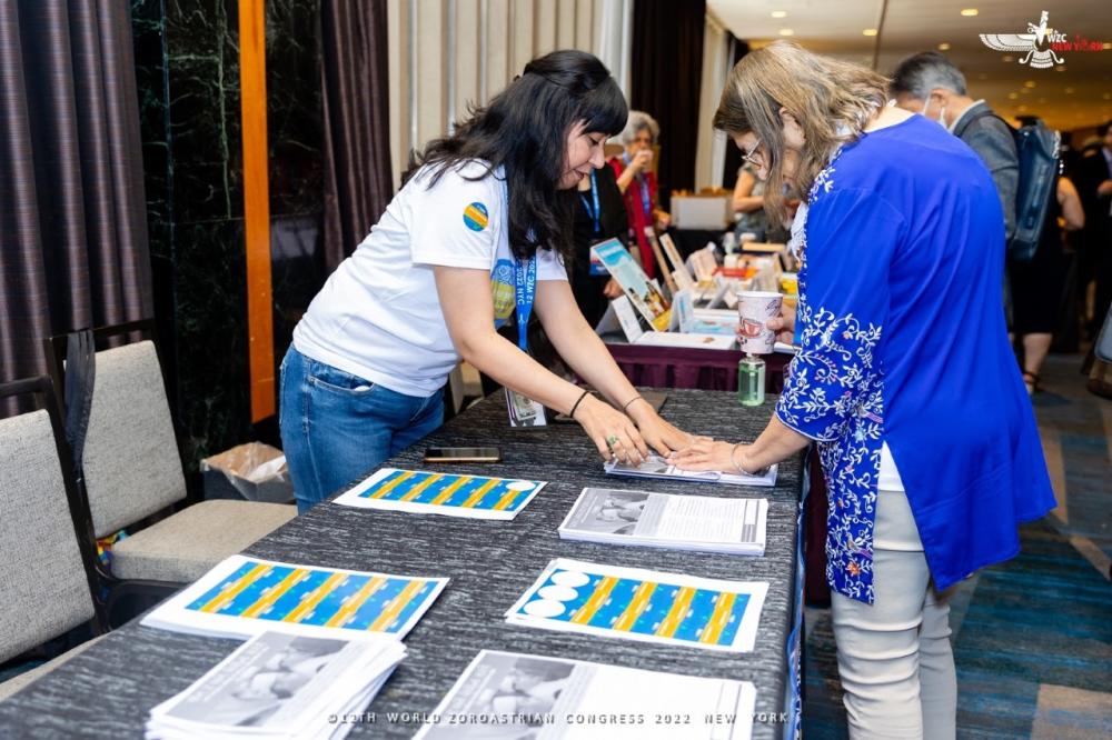 Project manager Nazneen Engineer standing at a table with an attendee of the World Zoroastrian Congress