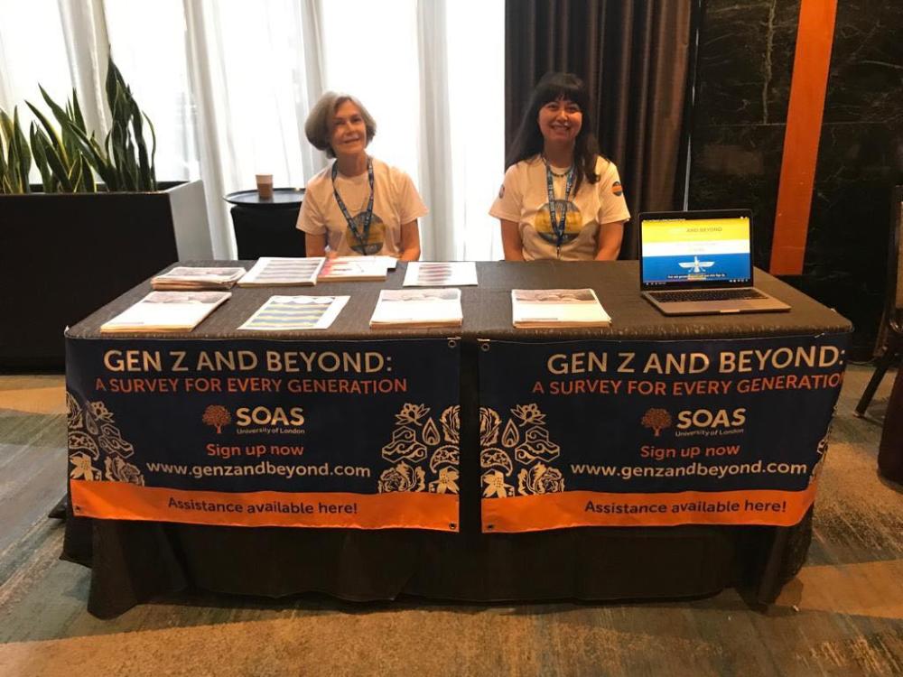Sarah Stewart and Nazneen Engineer sat at a table with a laptop and documents at the World Zoroastrian Congress