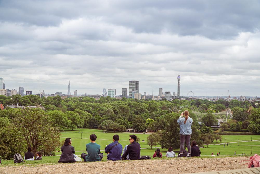 A group of young people look at the skyline of London, in Primrose Hill