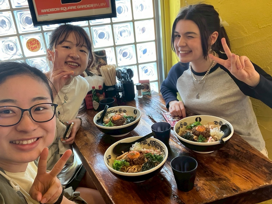 Three women at a restaurant smile and pose for the camera 