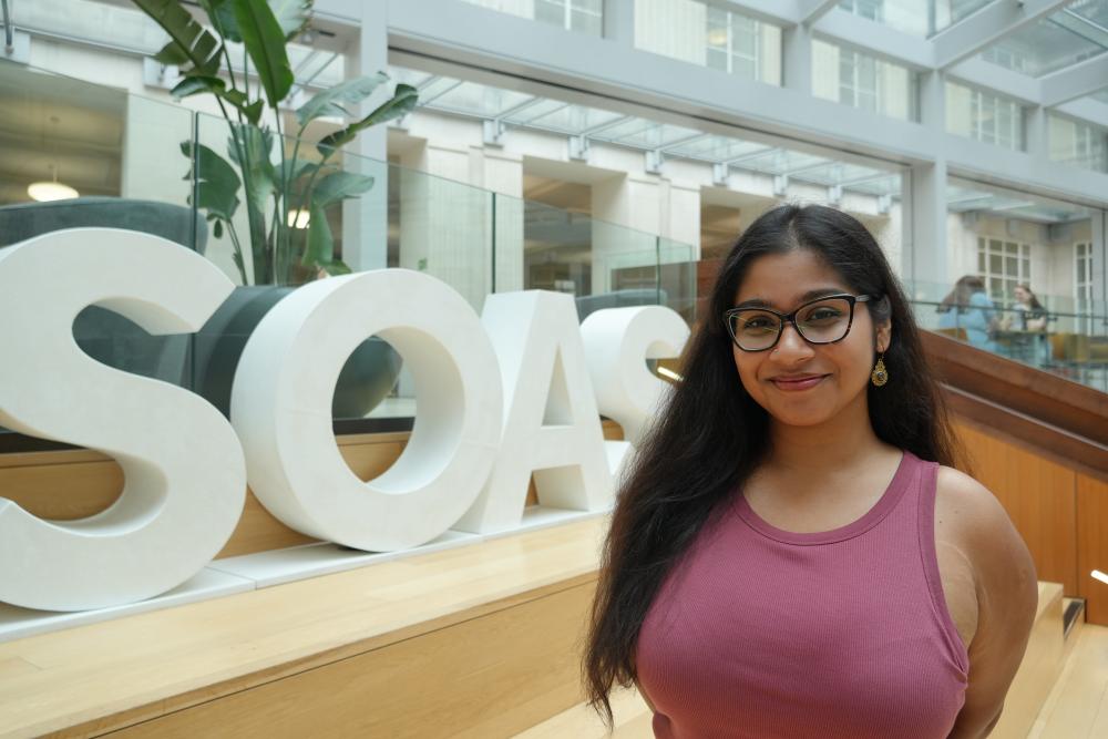 Young woman with long dark hair and glasses smiling at the camera