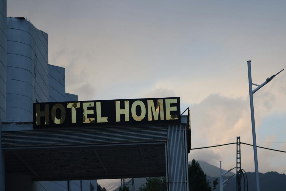 A broken sign reads 'Hotel Home' on the side of a building at dusk