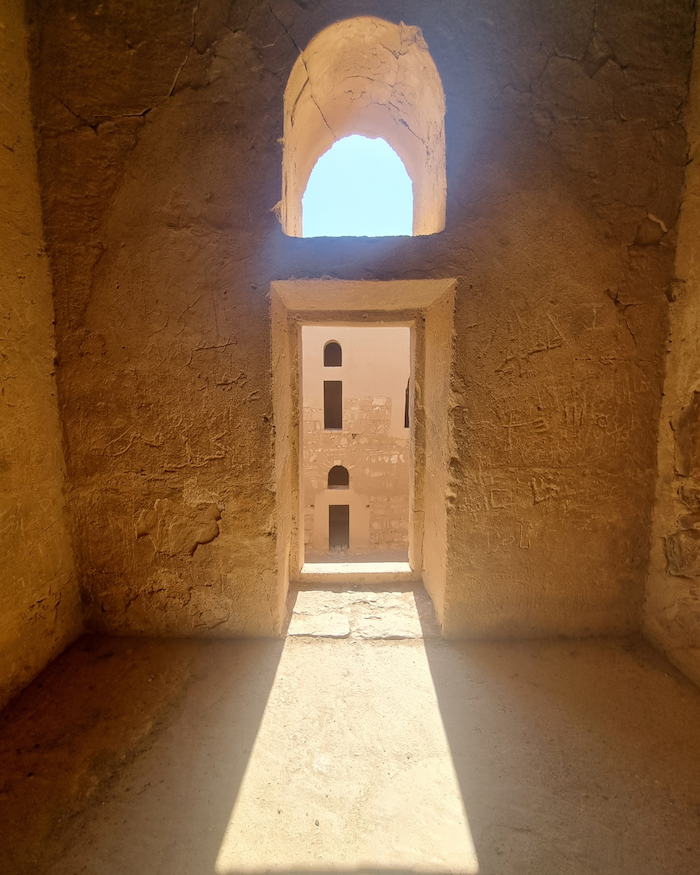 Sunlight streams through arched windows in a stone building