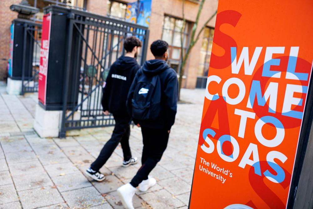 Two students walk through the Welcome to SOAS gate