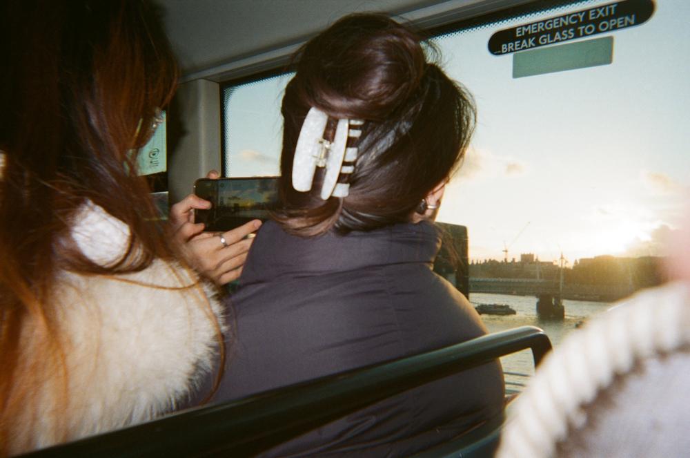 A woman takes a photo of a sunset through the window, capturing London. 