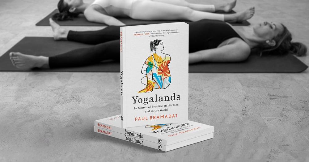 Yogalands Book Cover in front of two yogi practitioners lying in śavāsana.