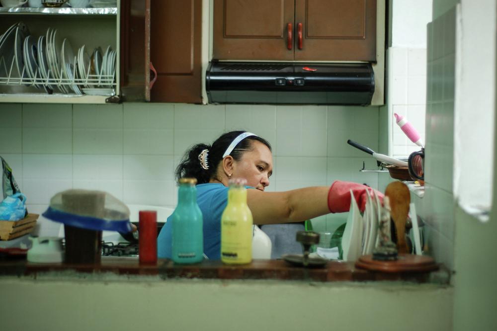 A woman does the washing up in a kitchen