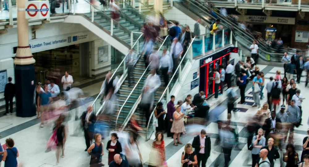 A busy London ungerground station with people bustling up and down an escalator.