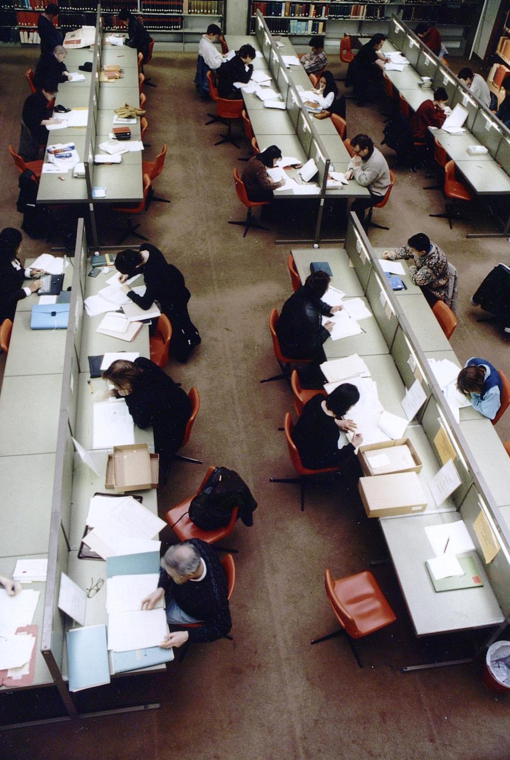 People on desks in the library with paper folders
