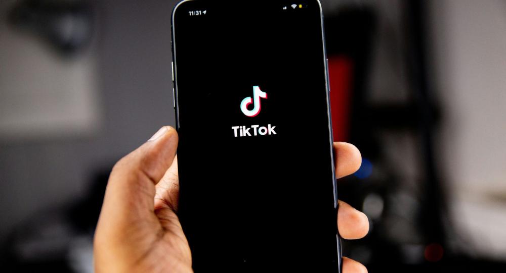 Hand holding a phone with the TikTok logo on it