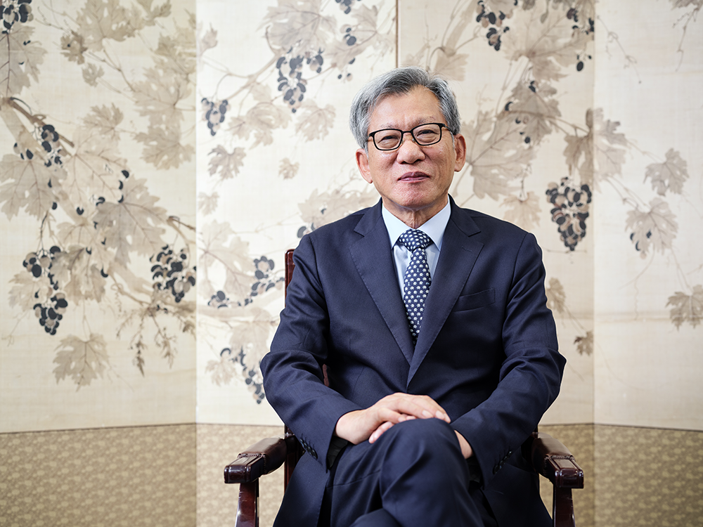 A man in suit, sitting in front of a decorative background